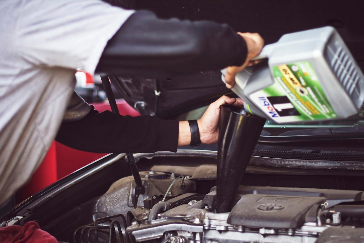 Mechanic pouring fresh engine oil into a car at a workshop